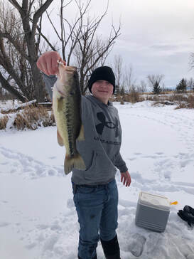 A young fisherman holding a large bass caught through the ice