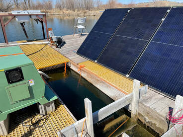 Solar panels sit on a floating dock next to a nanobubble aerator, waiting to be tested on Fish Fry Lake