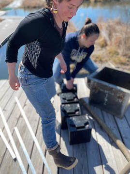 Two women students are shown hauling and positioning solar batteries into place on a Biohaven dock